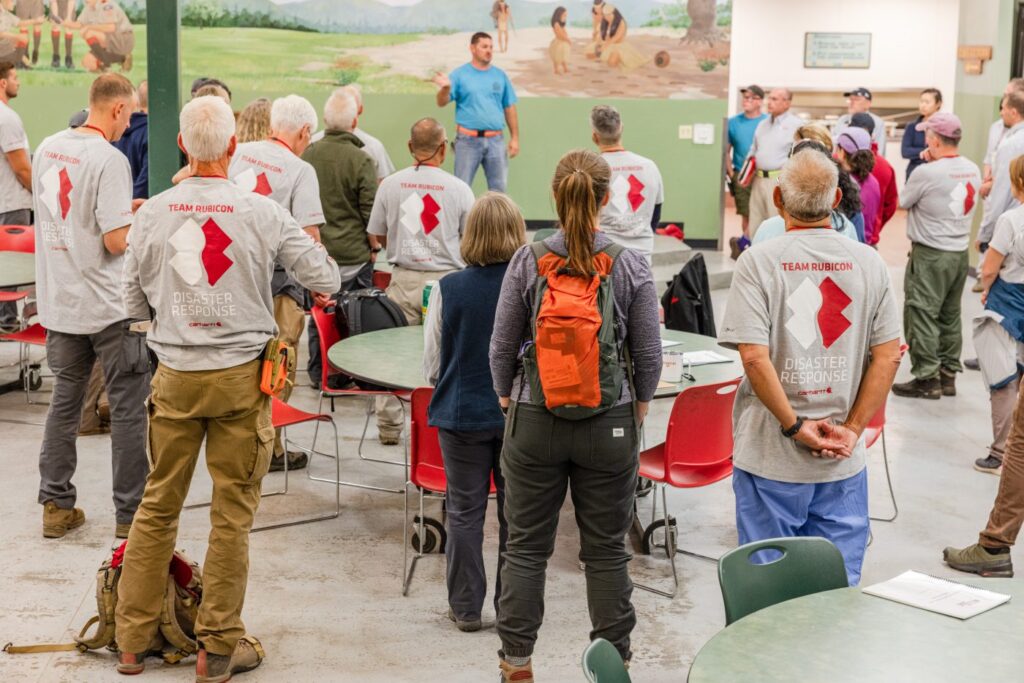 A group of volunteers listens to a speaker.