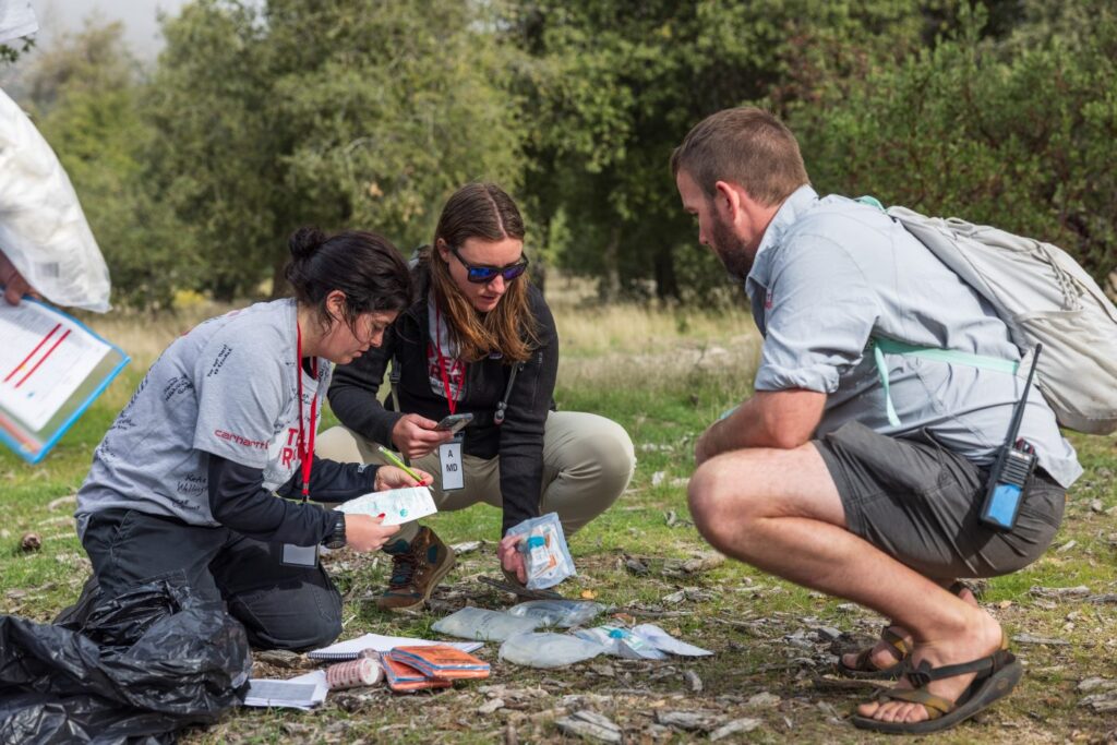 People look at medical supplies in woods.