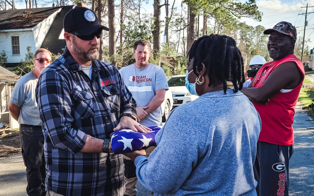 volunteer handing homeowner lost flag